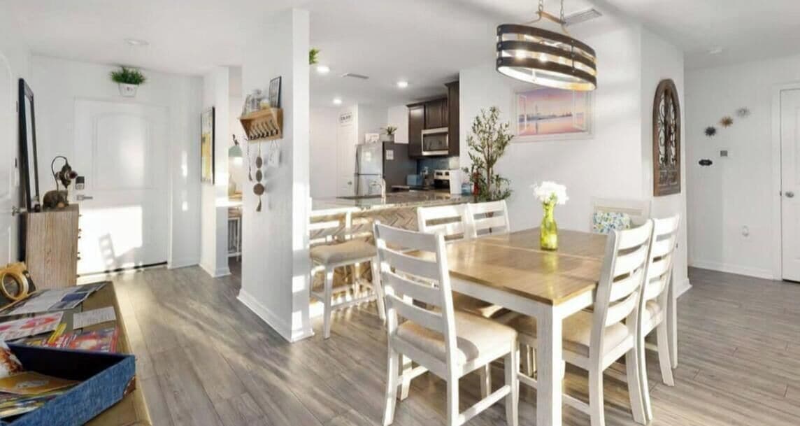 A modern kitchen with white cabinets, a wooden countertop, and a hanging light fixture.
