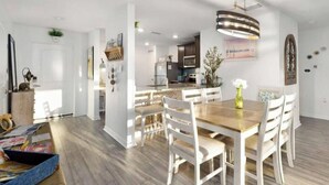 Una cocina moderna con armarios blancos, encimera de madera y una lámpara colgante.