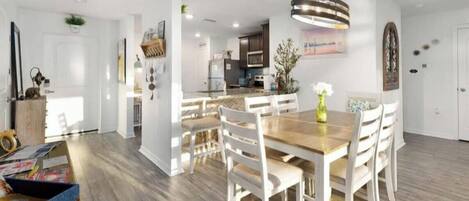 A modern kitchen with white cabinets, a wooden countertop, and a hanging light fixture.