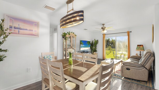 Un salón espacioso con una mesa de comedor de madera, un sofá color beige y un ventilador de techo.