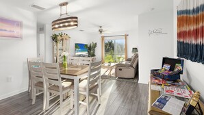 Una sala moderna con comedor, ventilador de techo y un amplio ventanal.