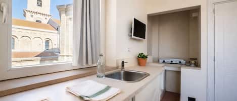 Een koelkast, kookgerei, borden en bestek, een eettafel