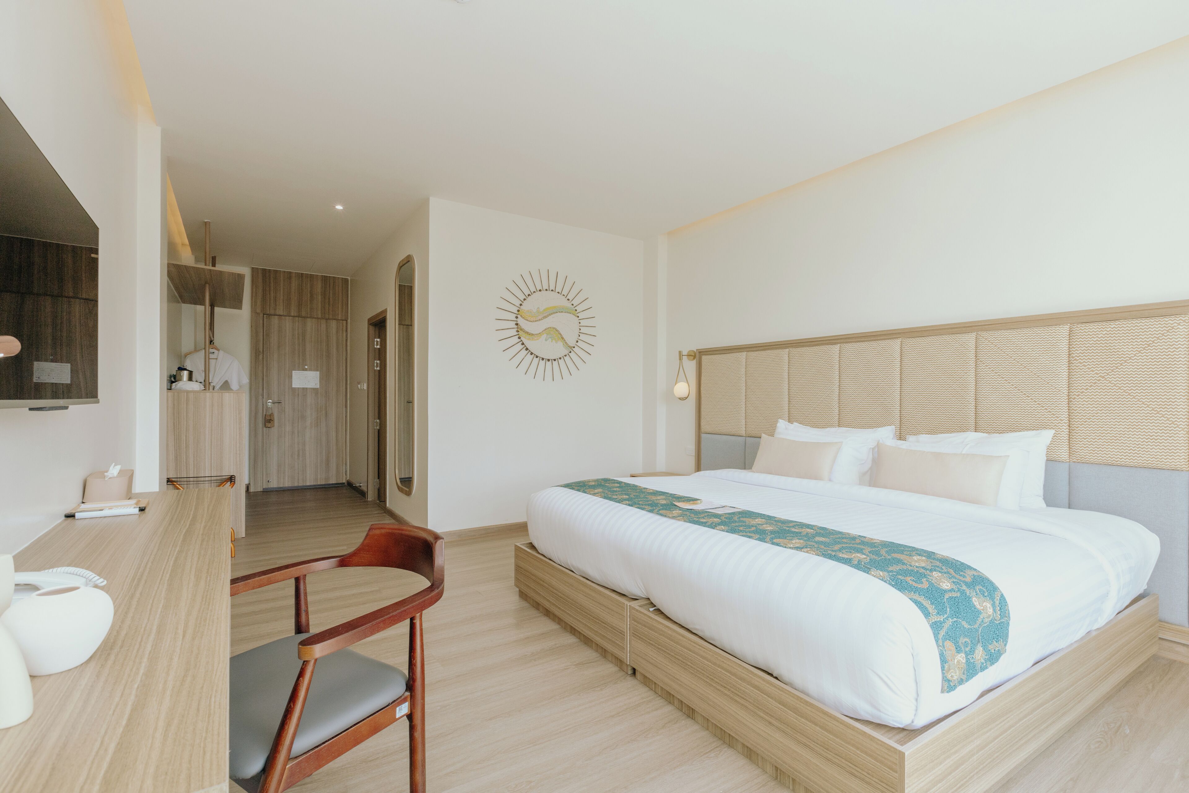 Une chambre d’hôtel moderne avec un grand lit, une tête de lit en bois et un bureau avec une chaise.