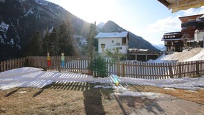 Eine Berglandschaft mit Holzzaun, einem kleinen Gebäude und blauem Himmel.