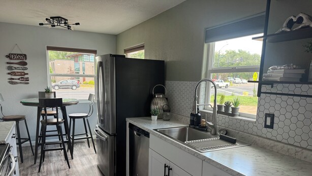 Una cocina moderna con un refrigerador de acero inoxidable, un lavavajillas integrado y un ventanal con vista a la calle.