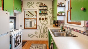 A kitchen with green cabinets, a white stove, and a window with a view of a garden.