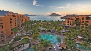 A resort with multiple buildings, a central pool area, and a view of the sea.