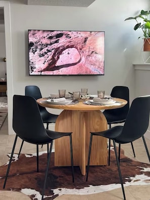 Ein Essbereich mit einem runden Holztisch, schwarzen Stühlen und einem großen, abstrakten Gemälde an der Wand.