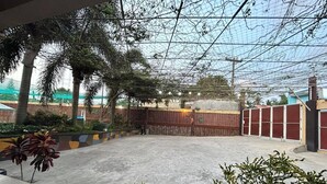 An outdoor area with a concrete floor, surrounded by a wooden fence and palm trees. - Serene Family Resort with Private Pool Pet Friendly Events and Vacations (Silang)