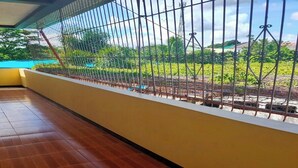 A room with a wooden floor and a view through a metal fence to a garden area. - Serene Family Resort with Private Pool Pet Friendly Events and Vacations (Silang)