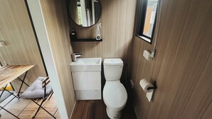 Un baño pequeño con lavamanos, inodoro y espejo blancos.