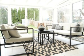 A sunlit patio area with a sofa, two chairs, a table, and a patterned rug. - Holiday Home 'Landhausglück' with Private Terrace, Private Garden and Wi-Fi (Geislingen)