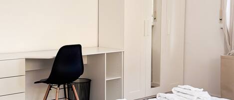 Une chambre à coucher comprenant un lit, un bureau avec une chaise, une armoire et une fenêtre avec des rideaux.