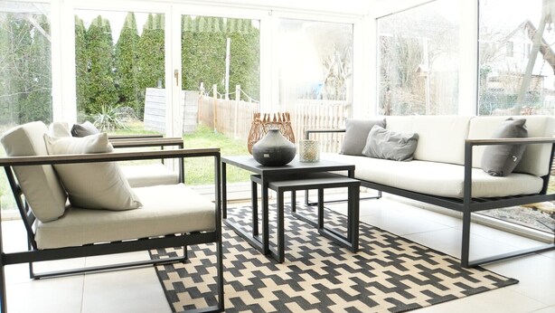 A conservatory with a sofa, chairs, a table, and a patterned rug. - Holiday Home 'Happiness' with Private Terrace, Private Garden and Wi-Fi (Geislingen)
