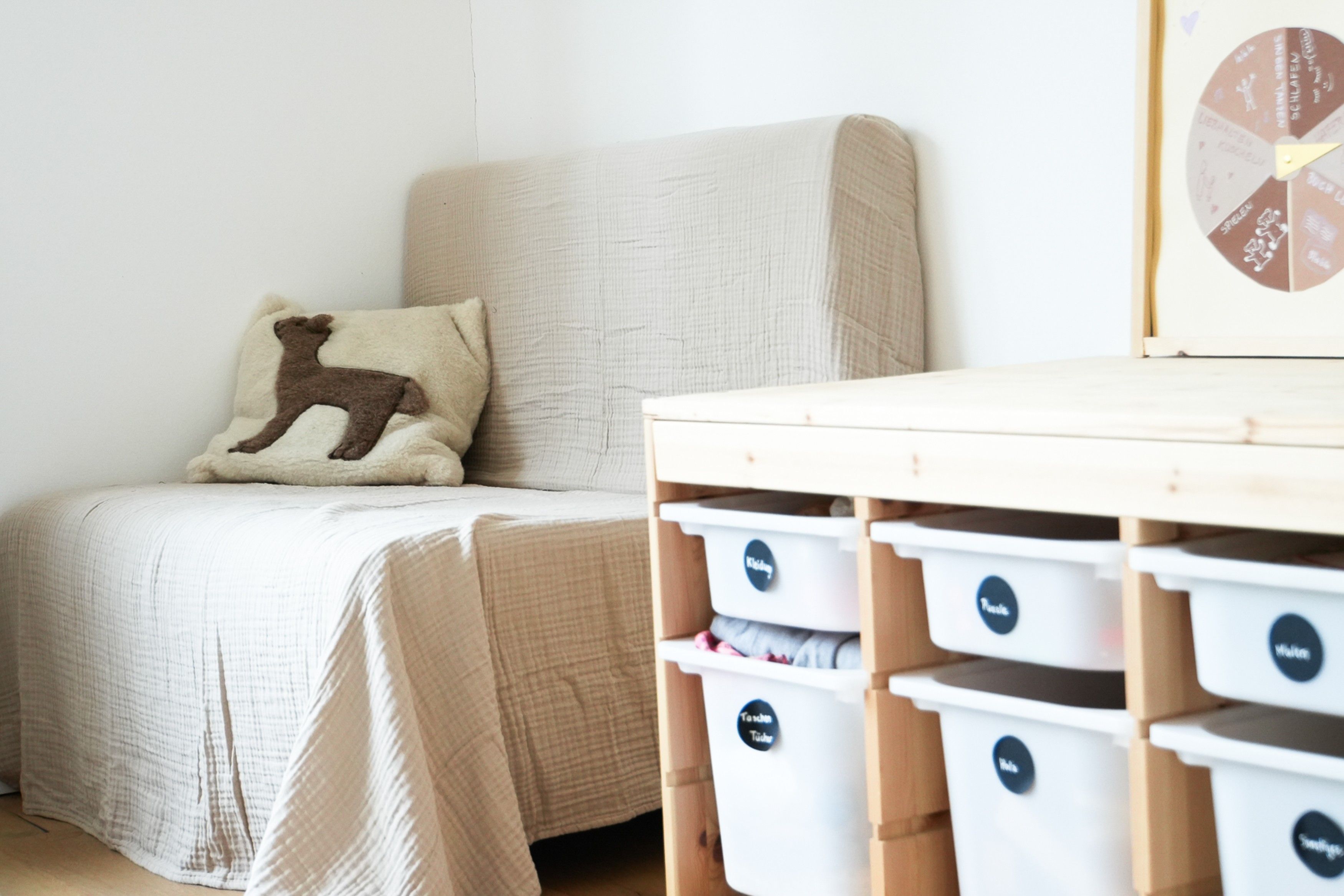 Ein Schlafzimmer mit einem Bett, einem Kissen mit Hirschmuster und Staufässern mit Beschriftungen.