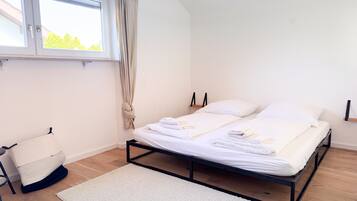 Ein Schlafzimmer mit Bett, Fenster, Vorhang, Nachttisch und Stuhl.