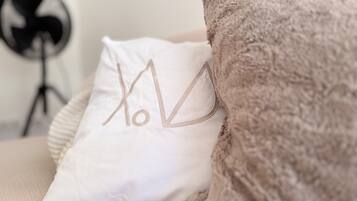 A white pillow with embroidered text on a beige sofa.