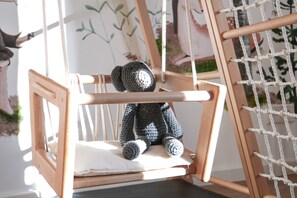A wooden chair with a cushion, a knitted bear toy, and a macrame wall hanging. - Holiday Home 'Landhausglück' with Private Terrace, Private Garden and Wi-Fi (Geislingen)