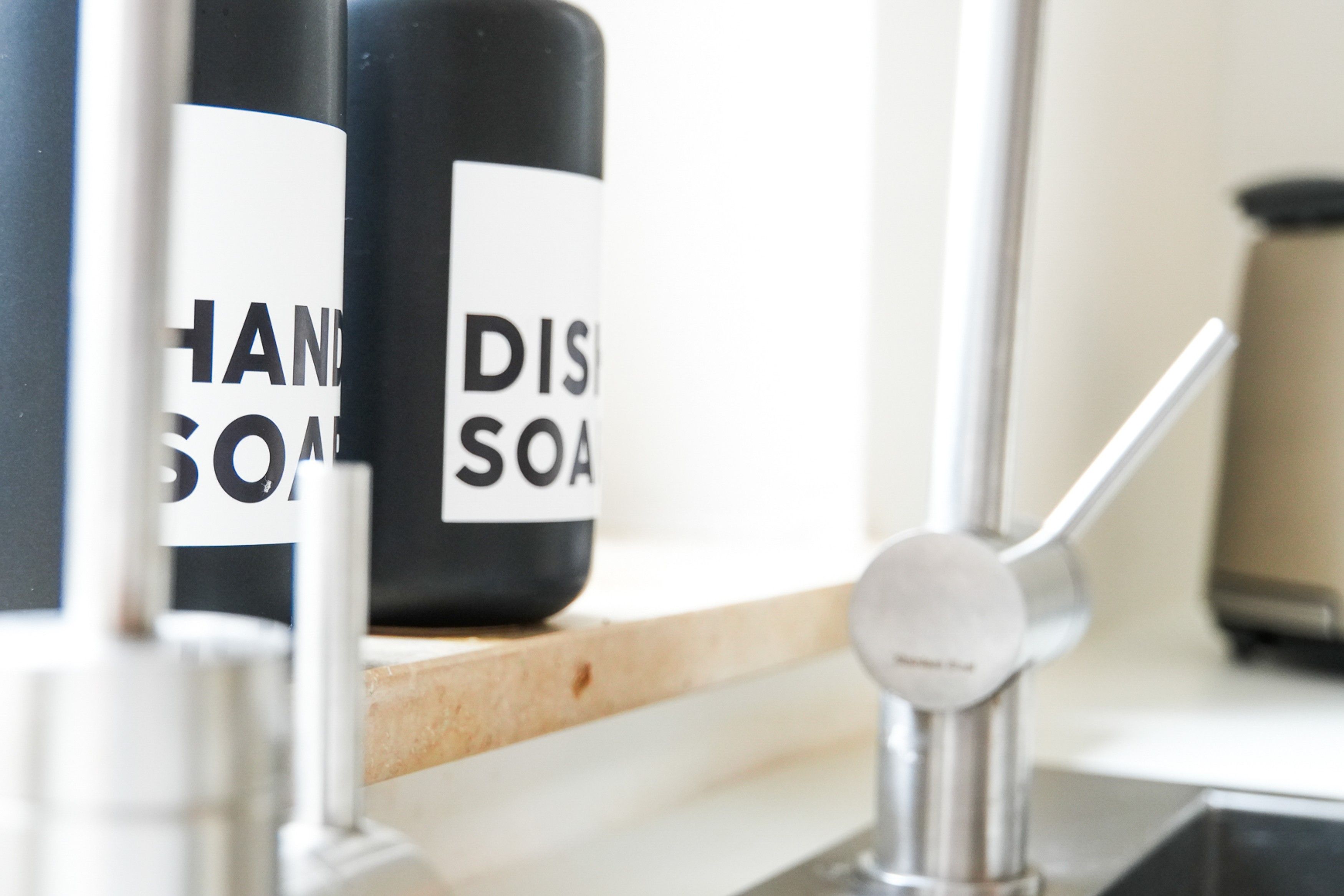 Una encimera de cocina con dos botellas de jabón para manos y platos.