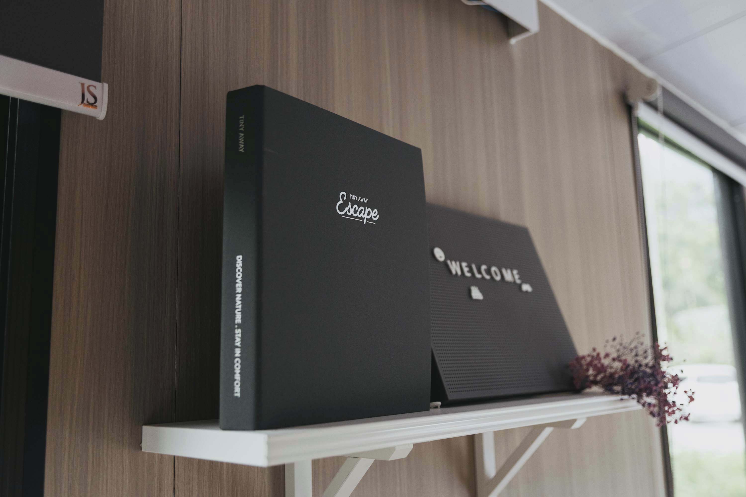 Un libro negro con el título 'Tiny Away Escape' sobre una estantería blanca.