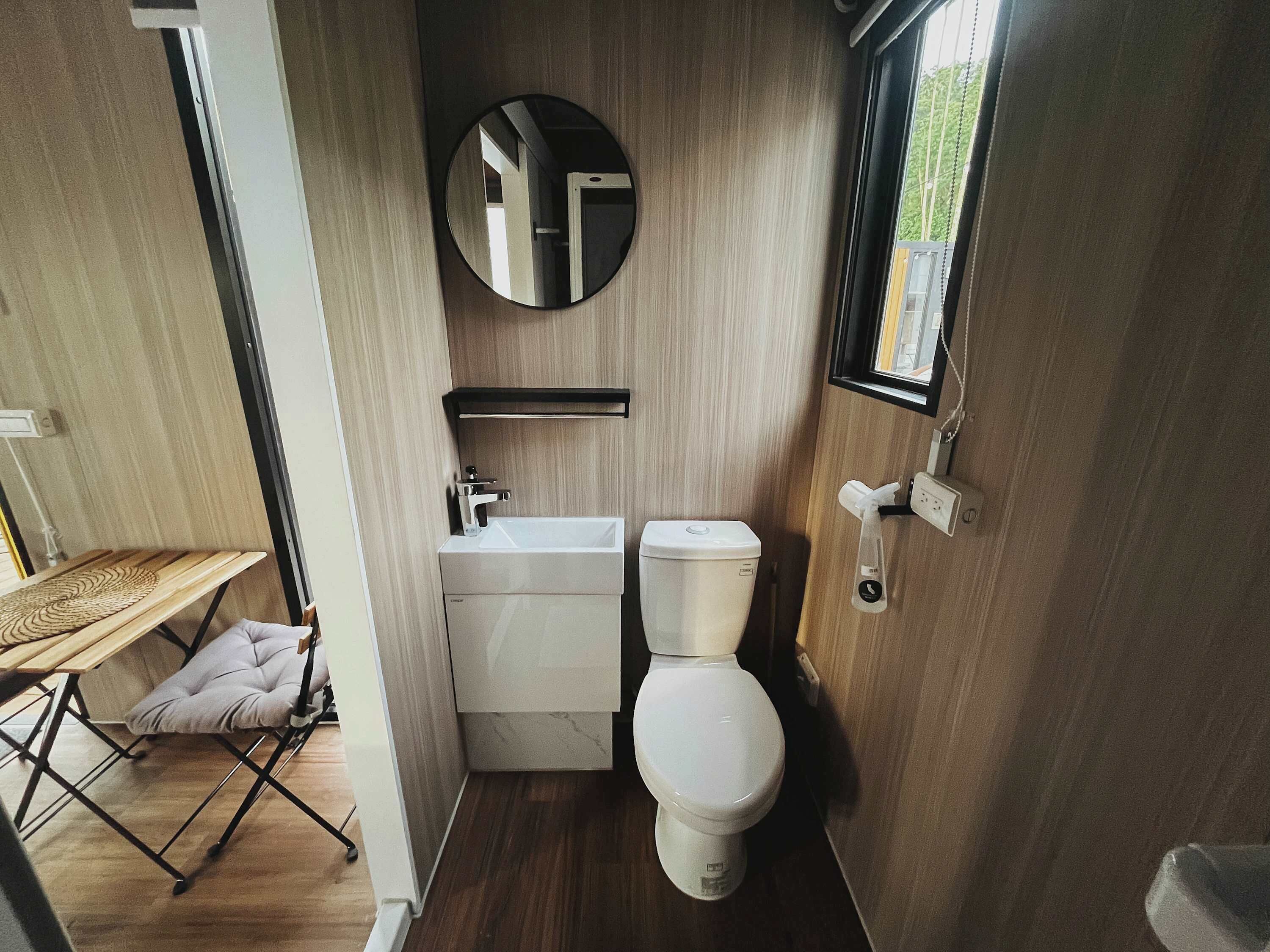 A compact bathroom with a toilet, sink, and mirror.