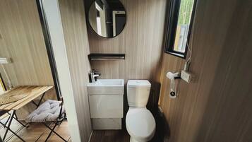 A compact bathroom with a toilet, sink, and mirror.