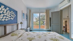 A bedroom with a bed, a nightstand, a window with curtains, and a view of the outside. - Casa Vignola, Capoliveri (Capoliveri)