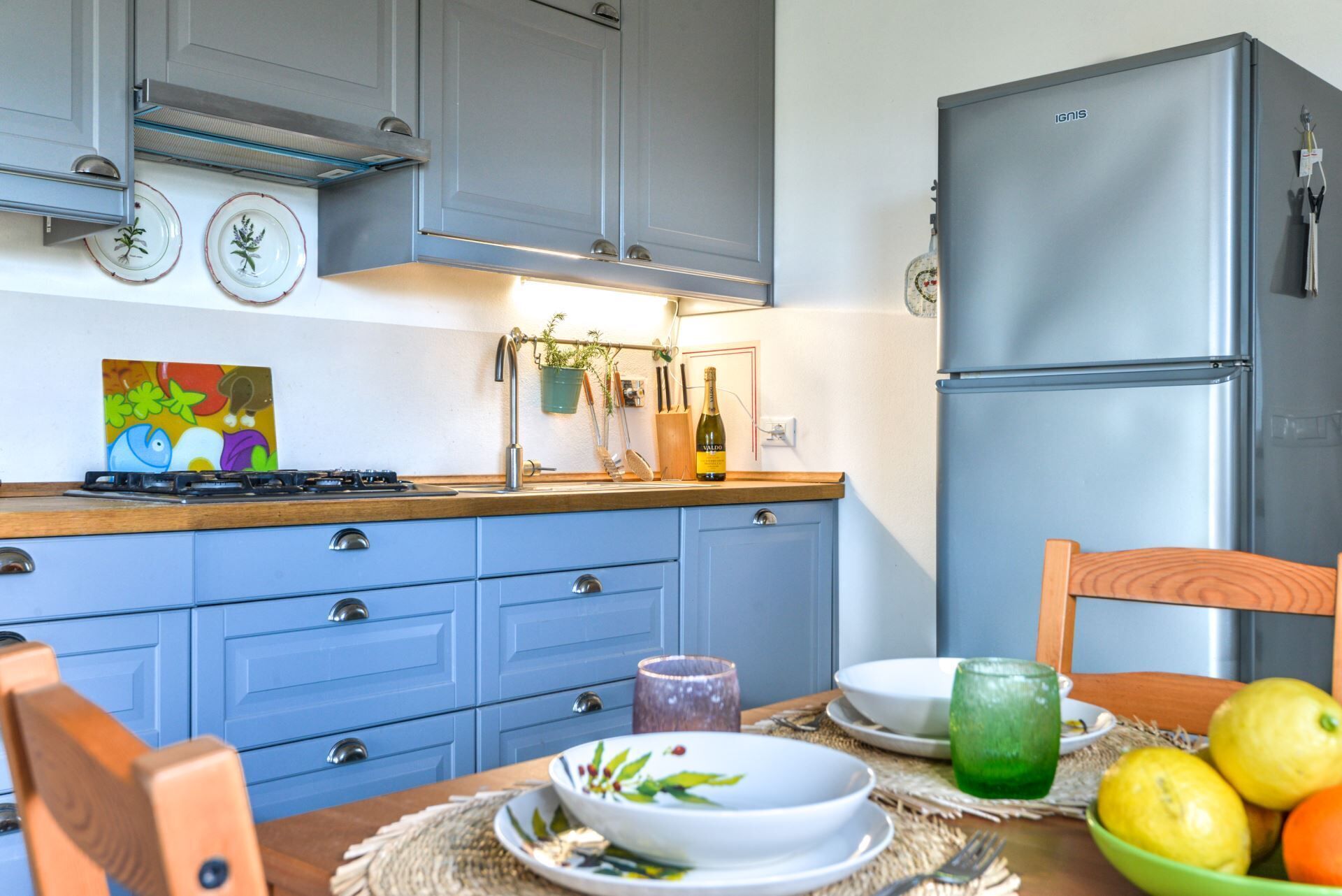Une cuisine avec des armoires bleues, un réfrigérateur en acier inoxydable et un plan de travail en bois.