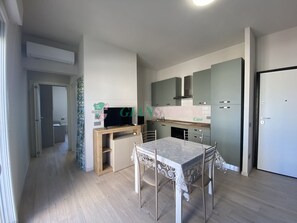 A modern kitchen with a dining area, built-in cabinets, and a flat-screen TV.