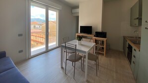 Eine moderne Wohnung mit Balkon, Essbereich, Küche und Fernseher.