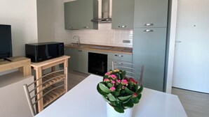 Eine moderne Küche mit grauen Schränken, einer Mikrowelle, einem Spülbecken und einem Geschirrspüler. Ein kleiner Tisch mit einer Pflanze darauf.