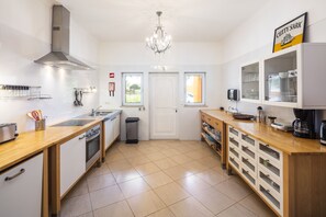 A modern kitchen with a central island, stainless steel appliances, and a chandelier.
