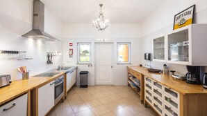 Een moderne keuken met een centraal eiland, roestvrijstalen apparatuur en een kroonluchter.