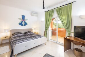 A bedroom with a bed, a TV, a desk, and a balcony with curtains. - Villa Diamante Luxury villa with private pool (Lagoa)