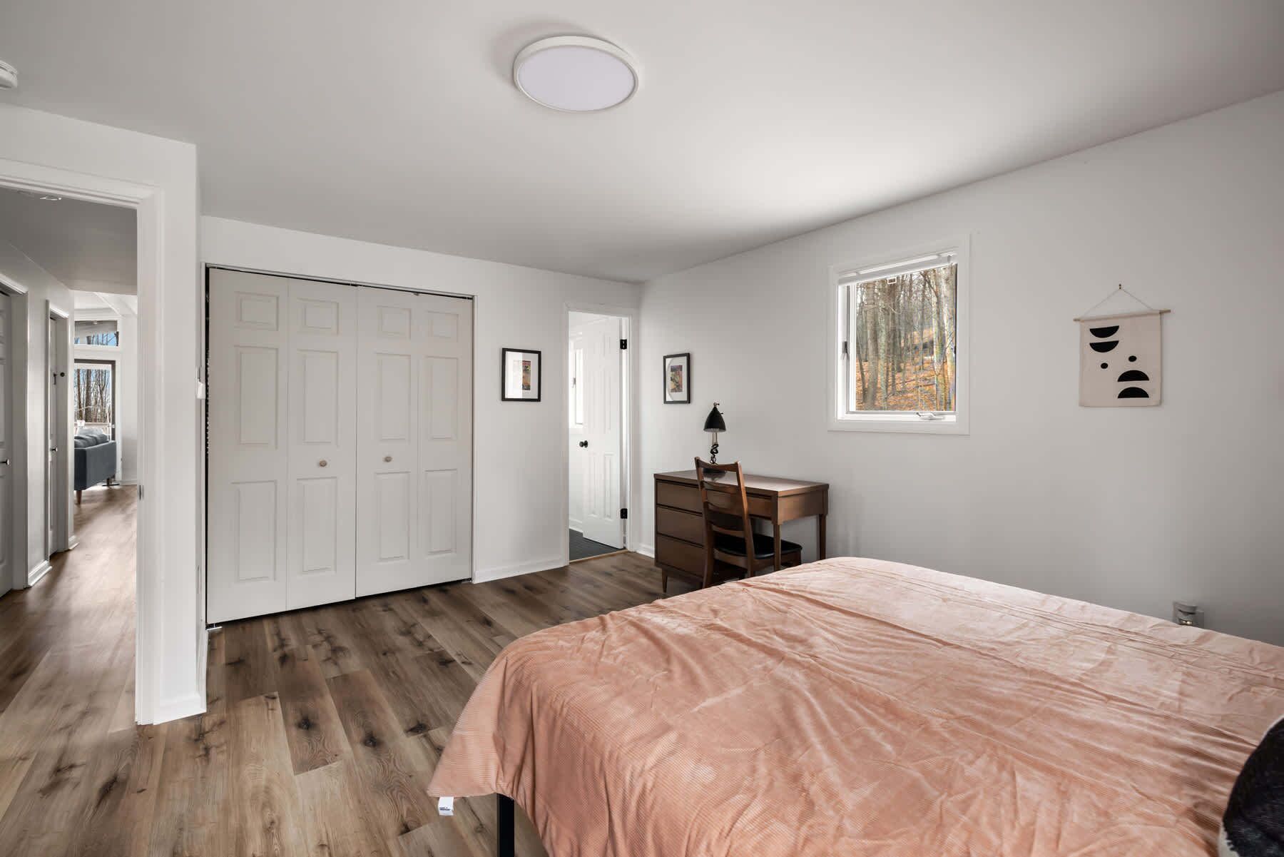 A bedroom with a bed, a desk, and a window.