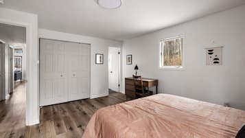 A bedroom with a bed, a desk, and a window.