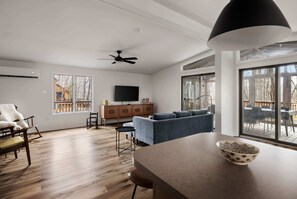 A modern living room with a sofa, a dining table, and a TV.
