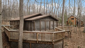 A cabin with a glass-enclosed deck, surrounded by trees.