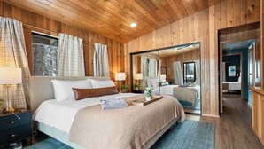 Une chambre aux murs lambrissés, avec un grand lit, des lampes de chevet et un miroir.