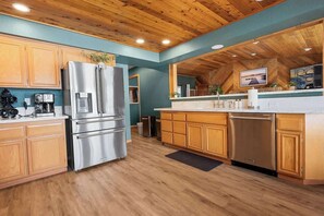 Una cocina moderna con armarios de madera, electrodomésticos de acero inoxidable y techo de madera.