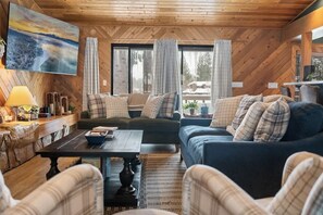 Una sala de estar acogedora con techo de madera, un cuadro grande, un conjunto de sofás y una mesa de centro.