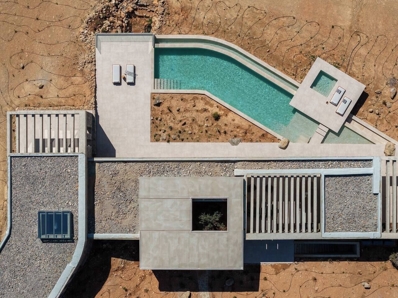 An aerial view of a modern resort with a swimming pool, outdoor seating, and a covered area.
