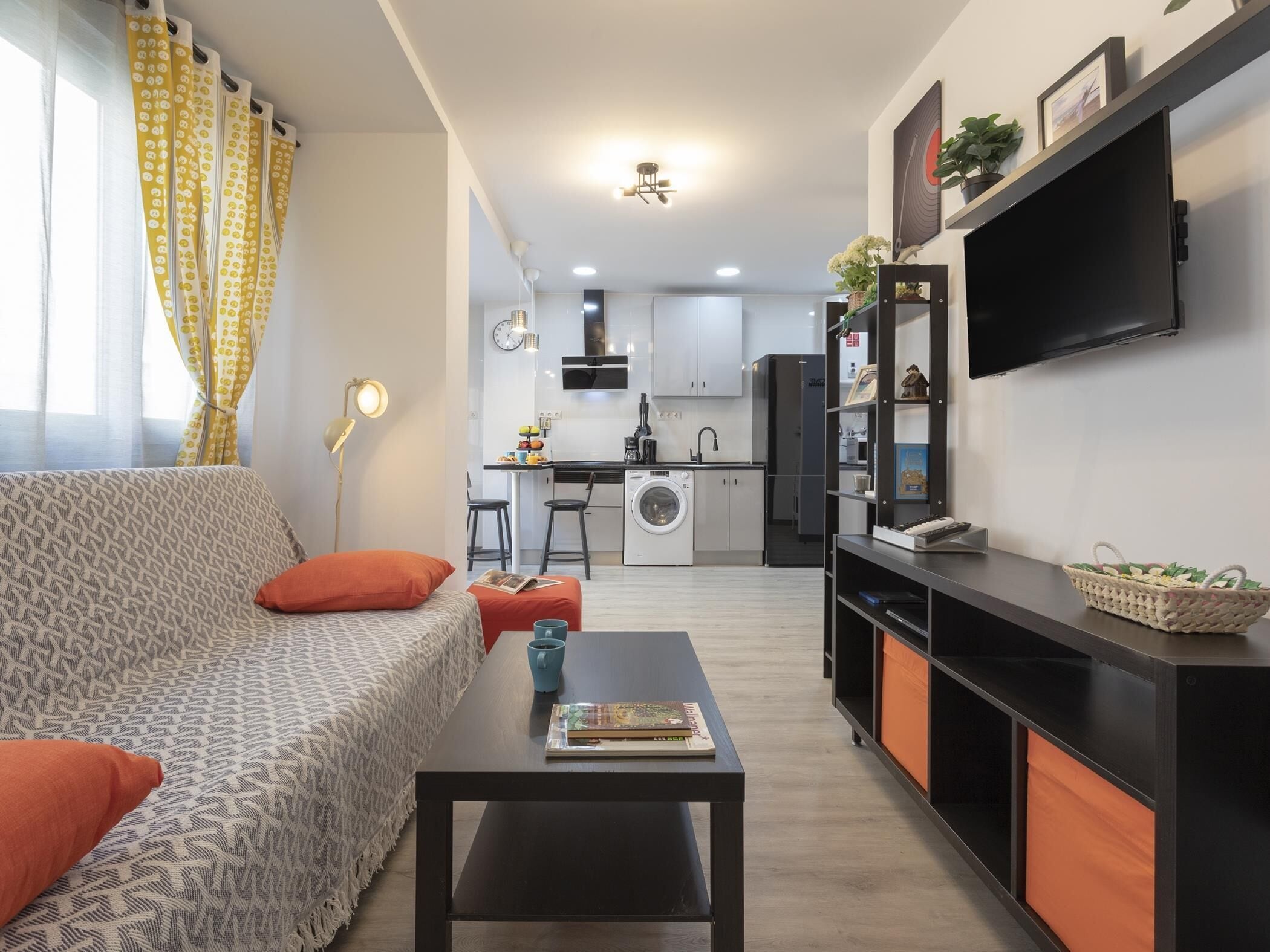 Uma sala de estar moderna com um sofá, mesa de centro e uma TV sobre um suporte.