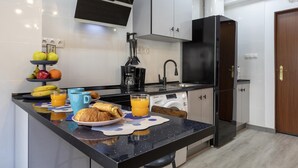 Cocina compacta con encimera negra, cafetera y lavadora.