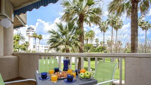A balcony with a table set for breakfast, featuring croissants, fruit, and orange juice.