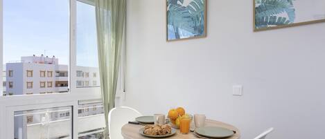 A balcony with a table set for breakfast, a city view, and two framed artworks on the wall.
