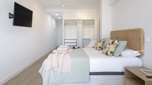 Een moderne slaapkamer met een bed, nachtkastje en een aan de muur bevestigde televisie.