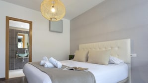 Ein modernes Schlafzimmer mit einem großen Bett, einem Nachttisch, einem Spiegel und einer außergewöhnlichen gewobenen Leuchte.