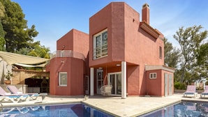 Ein modernes Haus mit Schwimmbad, Sitzgelegenheiten im Freien und einer Grillanlage.
