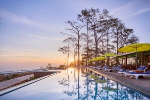 A poolside area with lounge chairs and umbrellas, surrounded by trees and overlooking a body of water. - Romhaey Kirirom Resort by EHM (Kampong Seila)